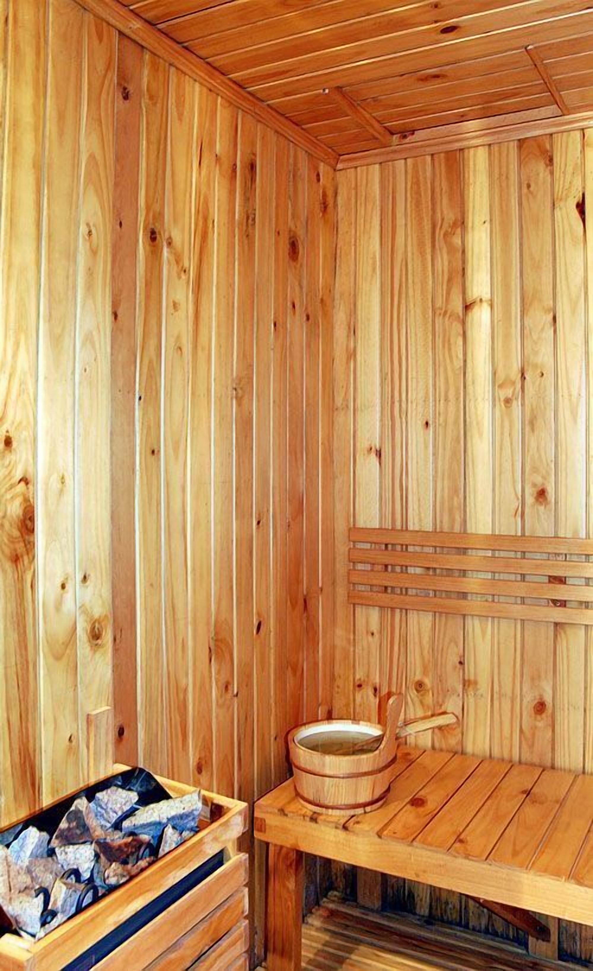 Uma sauna de madeira com um banco e uma bacia de pedra.
