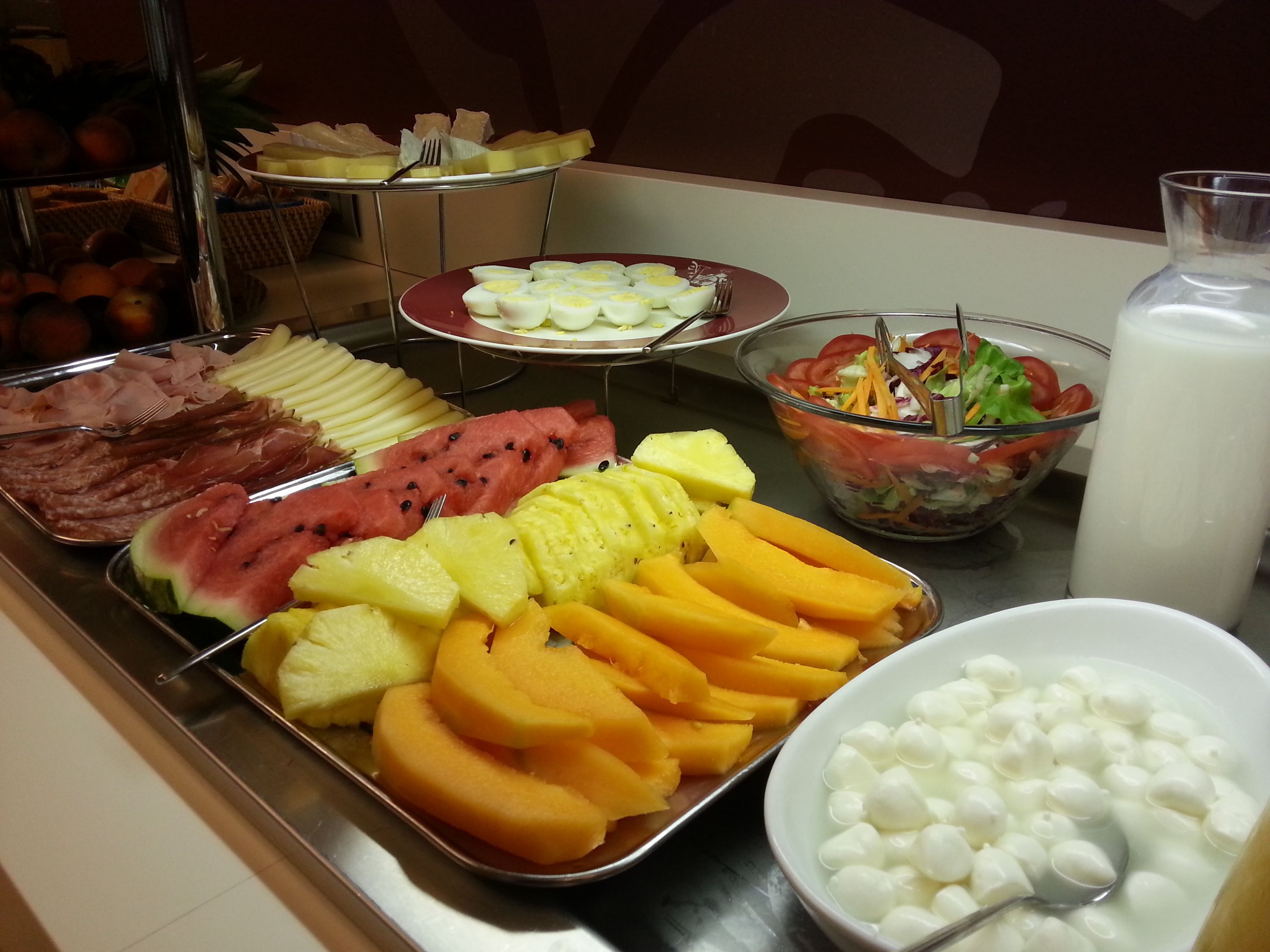 Un bufé con diversas frutas, verduras y una ensalada.