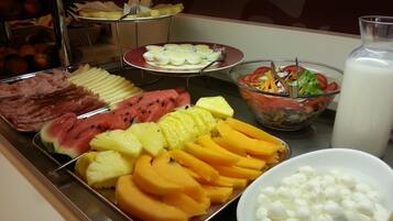A buffet with various fruits, vegetables, and a salad.