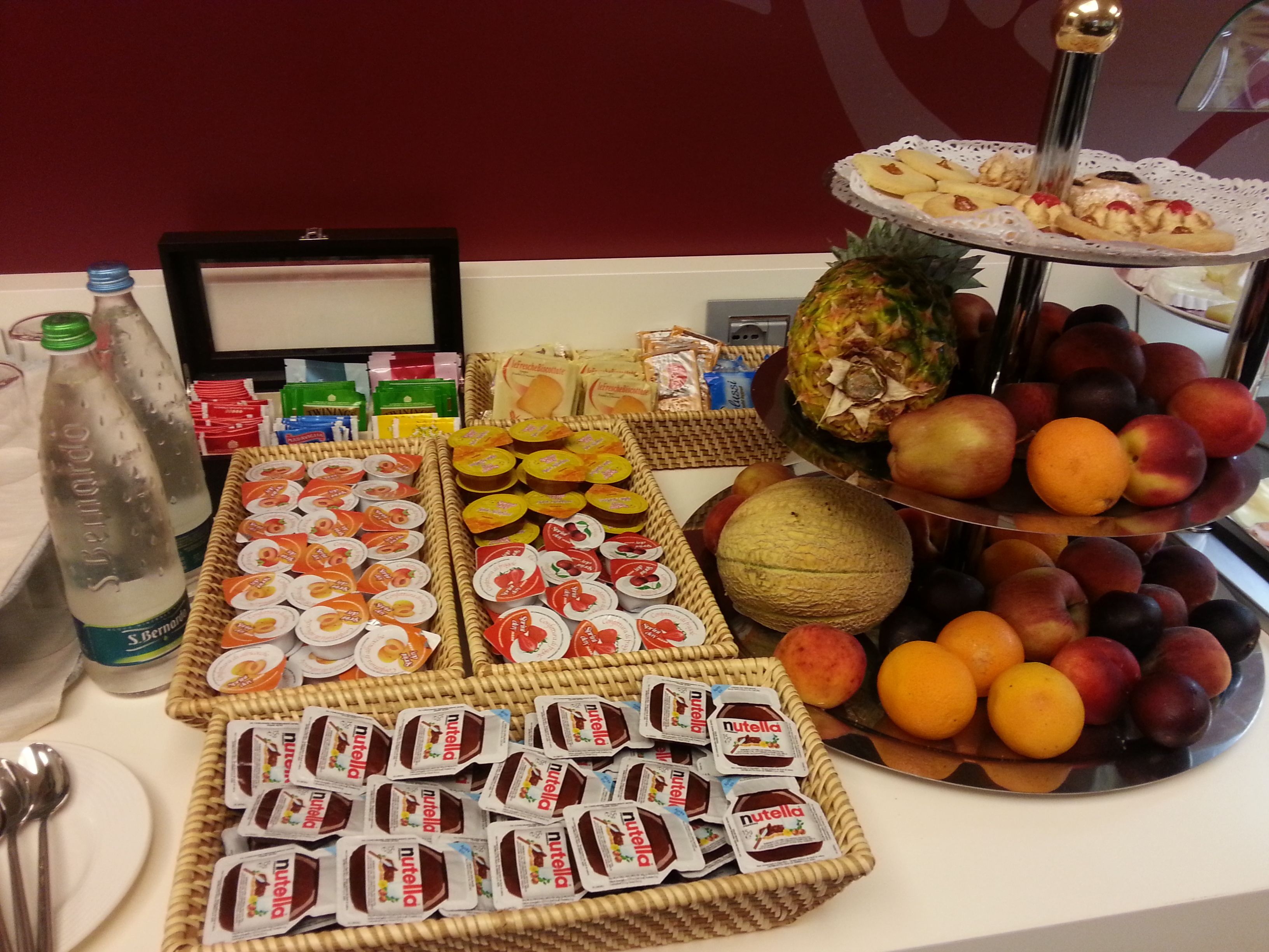 A buffet table with various food items including fruits, pastries, and packaged snacks.