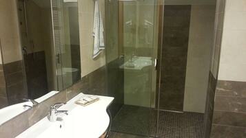 Un baño moderno con cabina de ducha de vidrio, un lavabo blanco y un espejo.