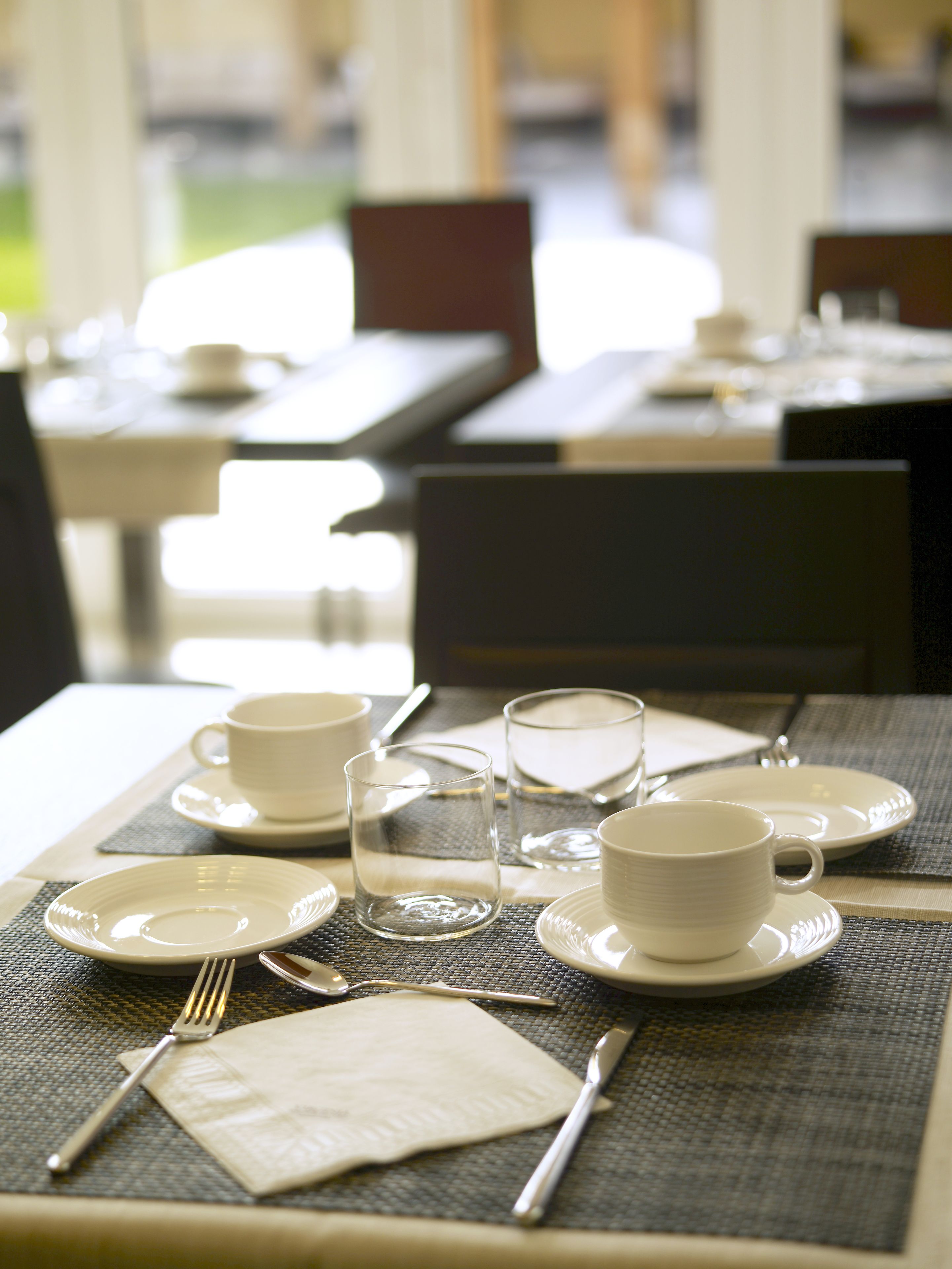 A dining table set with plates, glasses, cutlery, and a napkin, indicating a prepared table for dining.