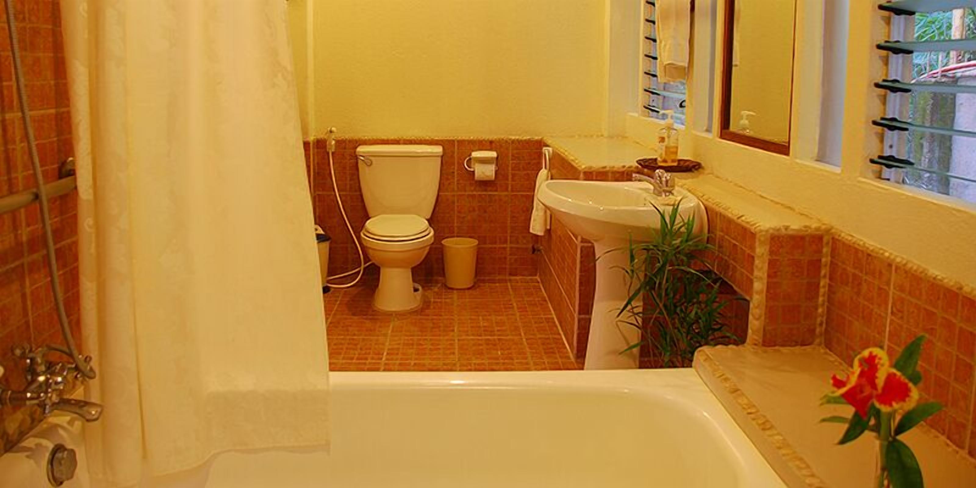 Une salle de bain équipée d’une baignoire, de toilettes, d’un lavabo et d’une fenêtre avec un porte-serviettes.