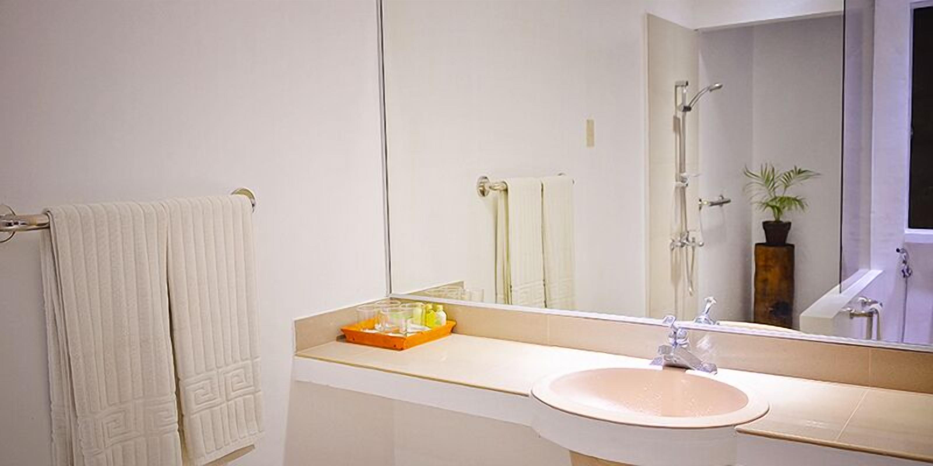 A bathroom with a sink, mirror, towel rack, and a shower.