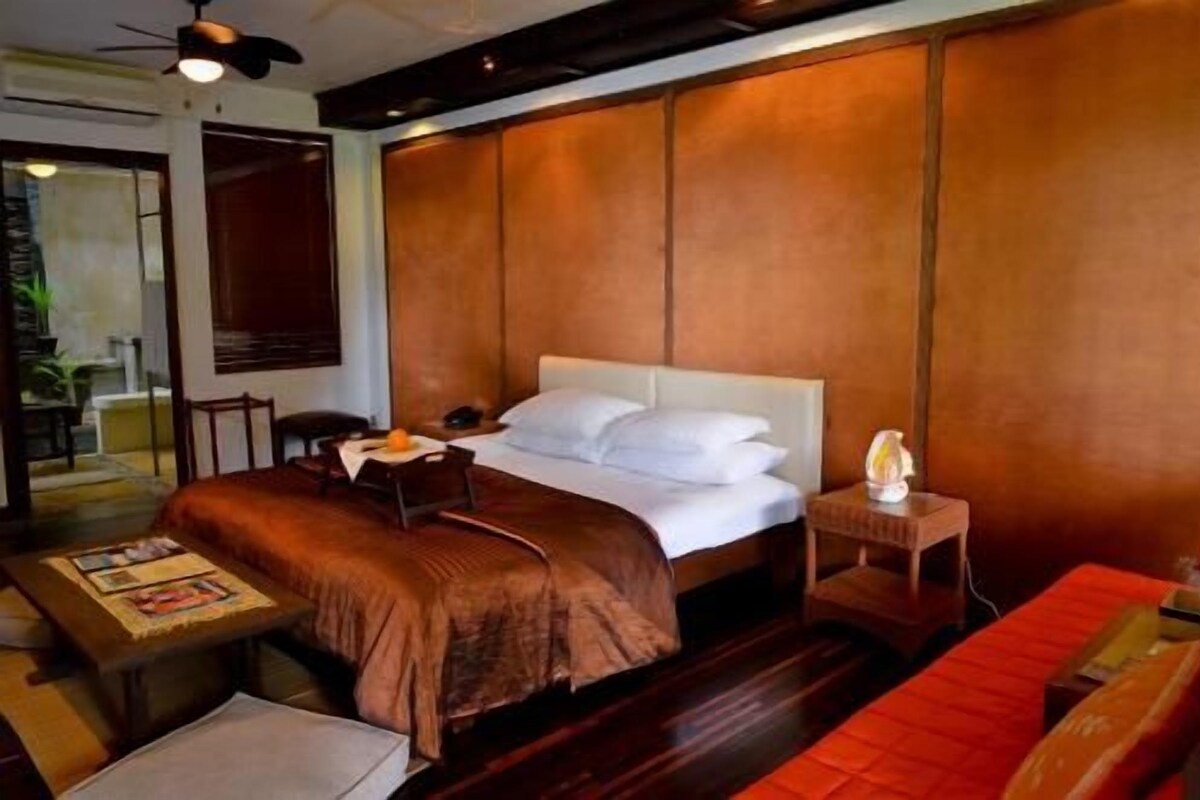 Un dormitorio con cama, mesita de noche y una pequeña mesa con lámpara.