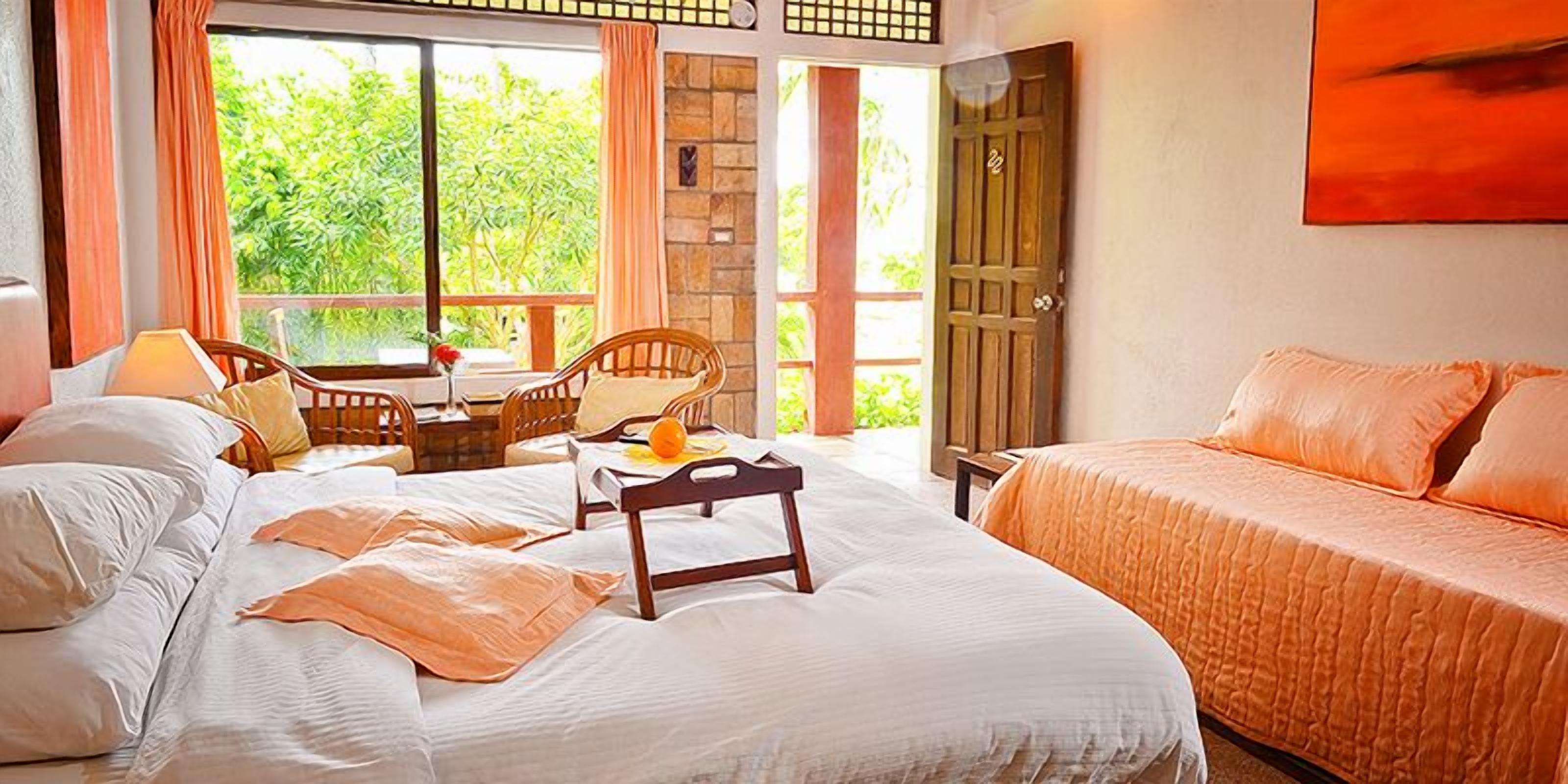Habitación de hotel con cama, una silla, una mesa con fruta y vistas a zonas verdes.