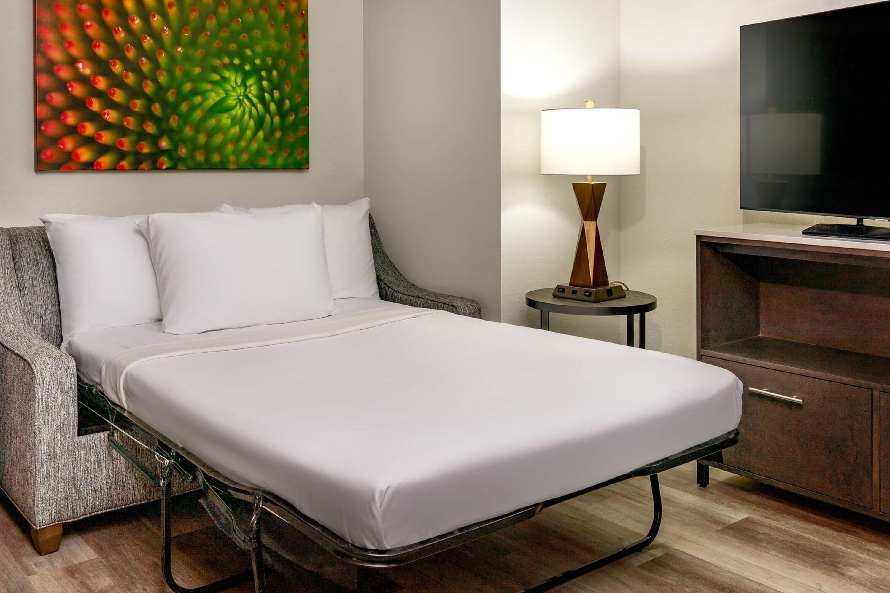 Ein Hotelzimmer mit Bett, Fernseher, Lampe und Schrank.