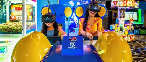 An indoor amusement arcade with VR gaming stations and various arcade games.