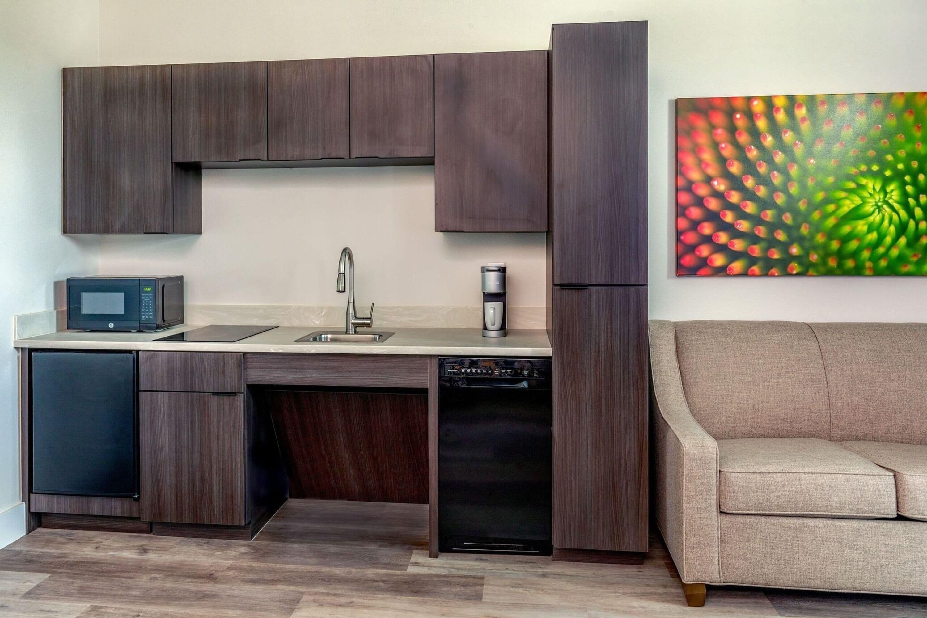 Una cocina moderna con armarios de madera oscura, microondas, cafetera y lavavajillas.