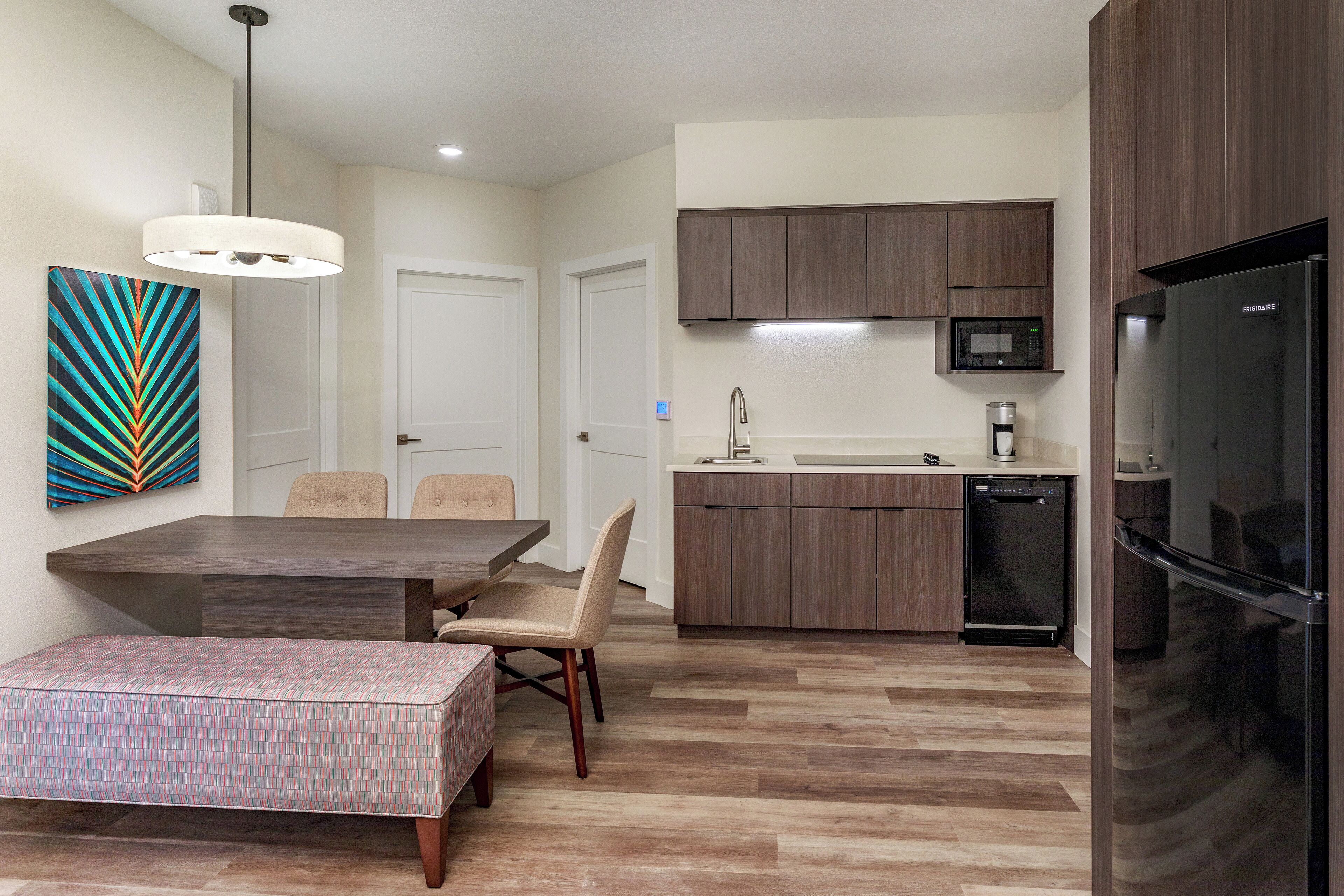 A modern kitchen with wooden cabinets, a built-in microwave, and a refrigerator.