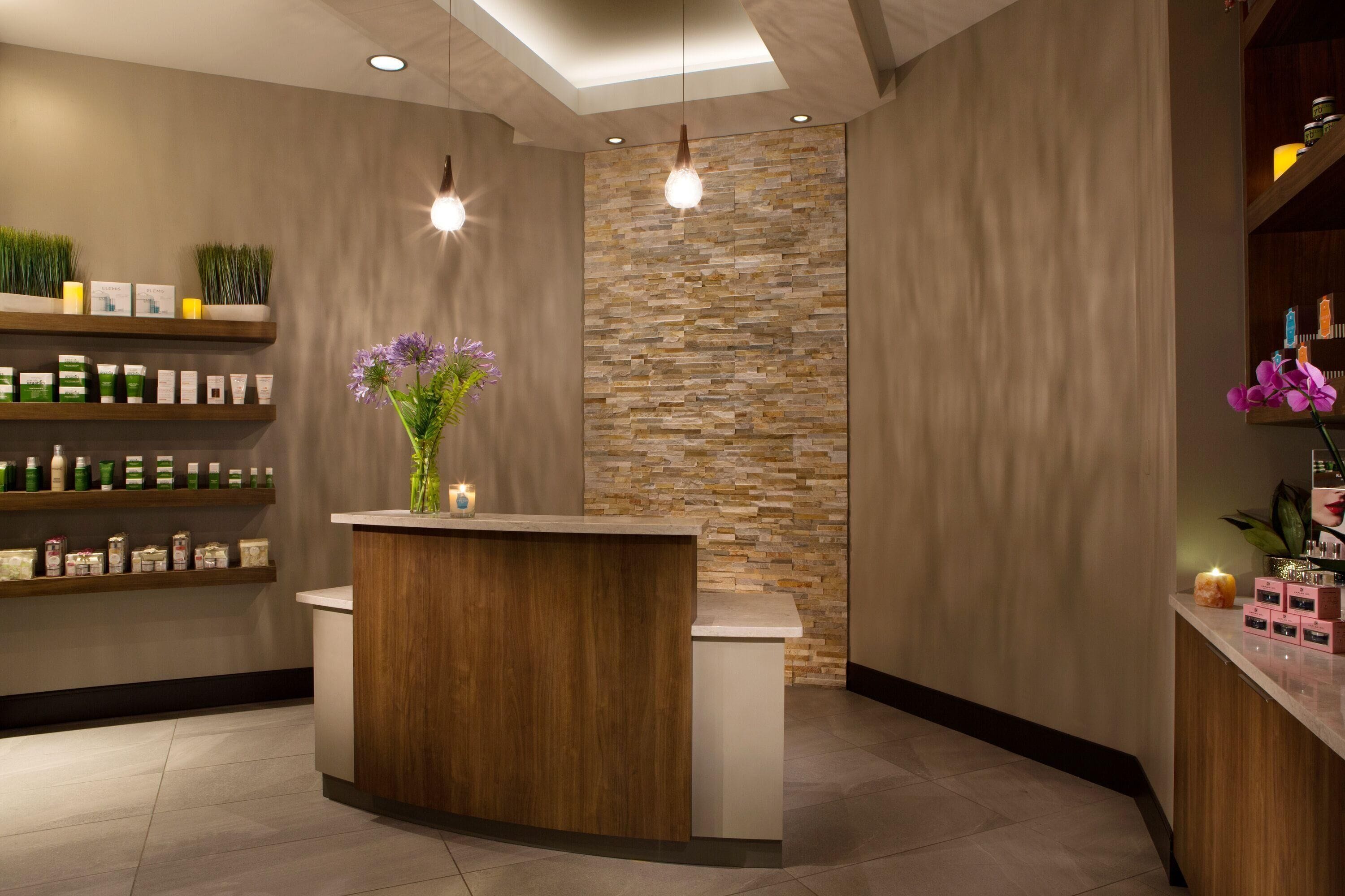 Un'area reception con scrivania in legno, scaffali con prodotti, una parete in pietra e lampade a sospensione.