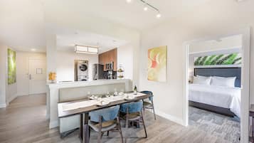 A modern apartment with a dining area, kitchenette, and a bedroom.