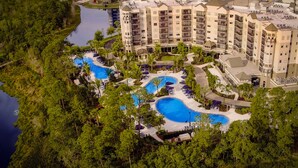 Un resort con varias piscinas rodeadas de exuberante vegetación y un gran edificio de hotel.