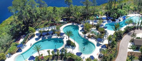 A resort with multiple swimming pools, lounge areas, and a view of the sea.