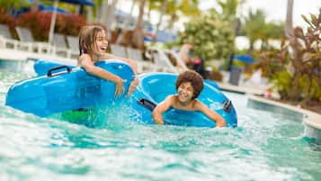 Two children in a pool with inflatable rafts.