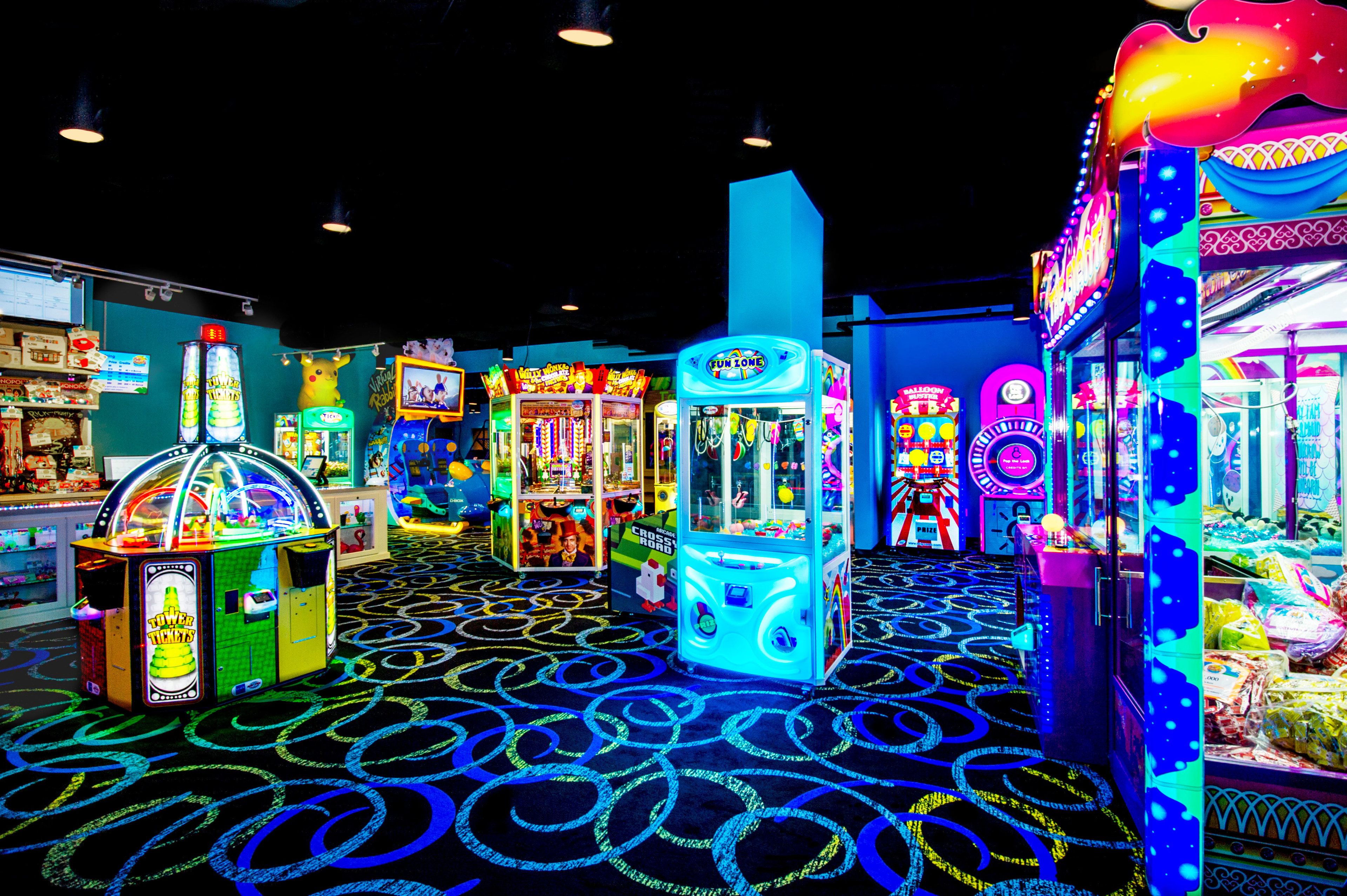 An indoor arcade with various gaming machines and a carpet with circular patterns.