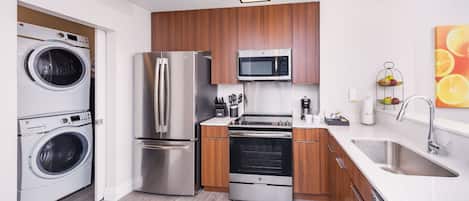 Una cocina compacta equipada con lavadora, refrigerador, microondas, horno y lavaplatos.