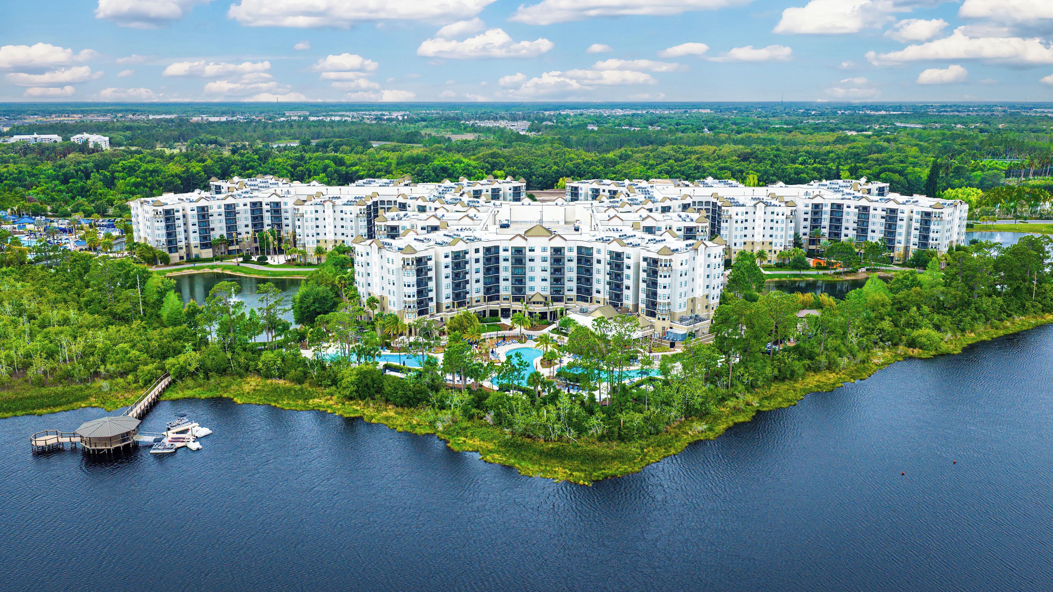 A large hotel complex with multiple buildings, a central courtyard, and a surrounding water body.
