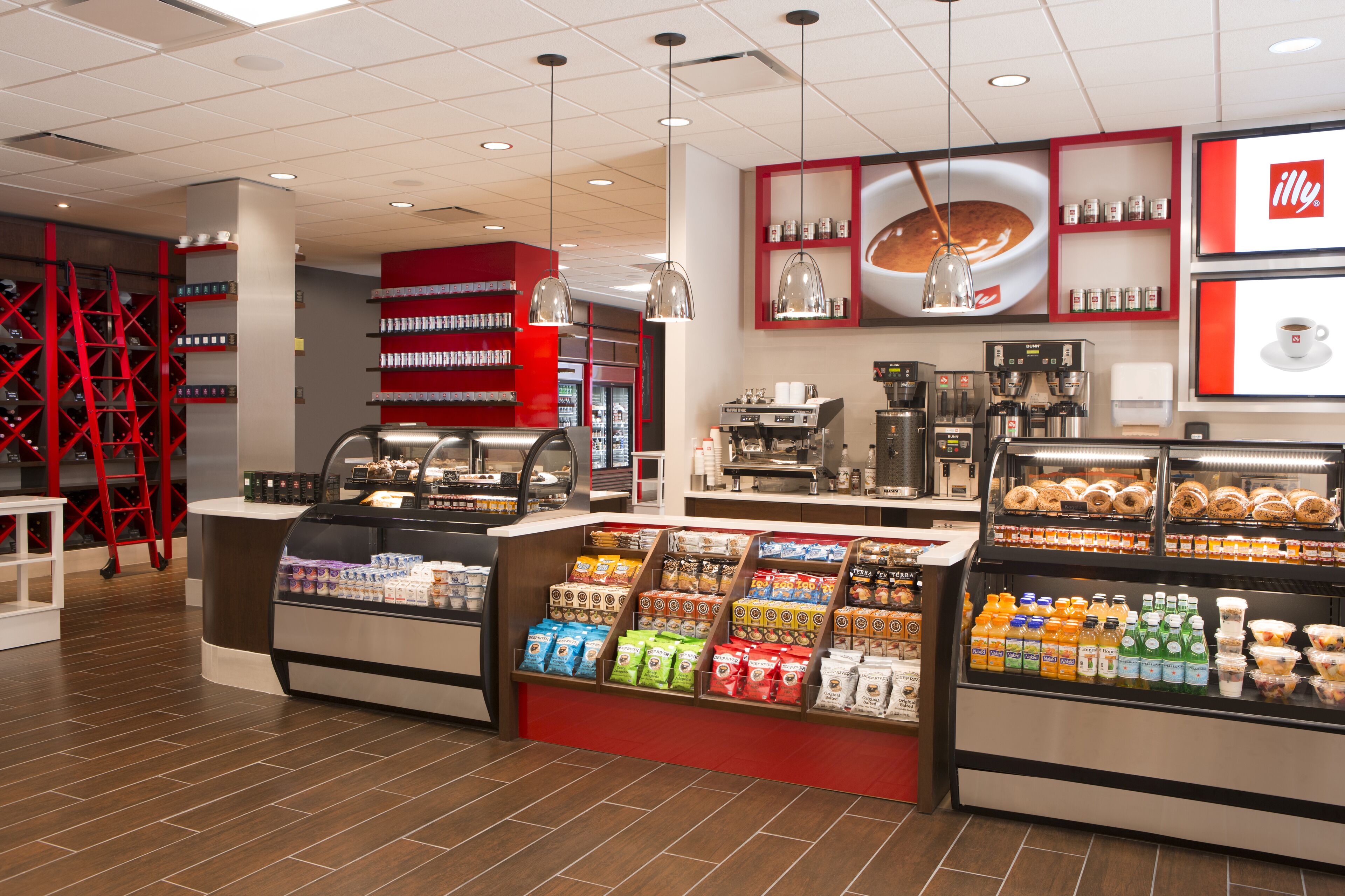 Un interior de cafetería moderna con una variedad de granos de café, pasteles y bebidas en exhibición.
