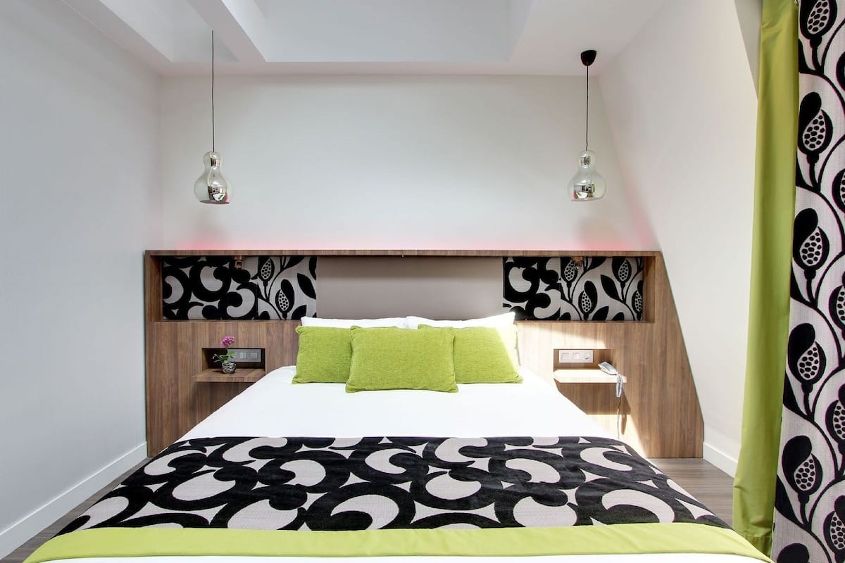 Um quarto moderno com uma cama grande, duas mesas de cabeceira e uma cabeceira decorativa.