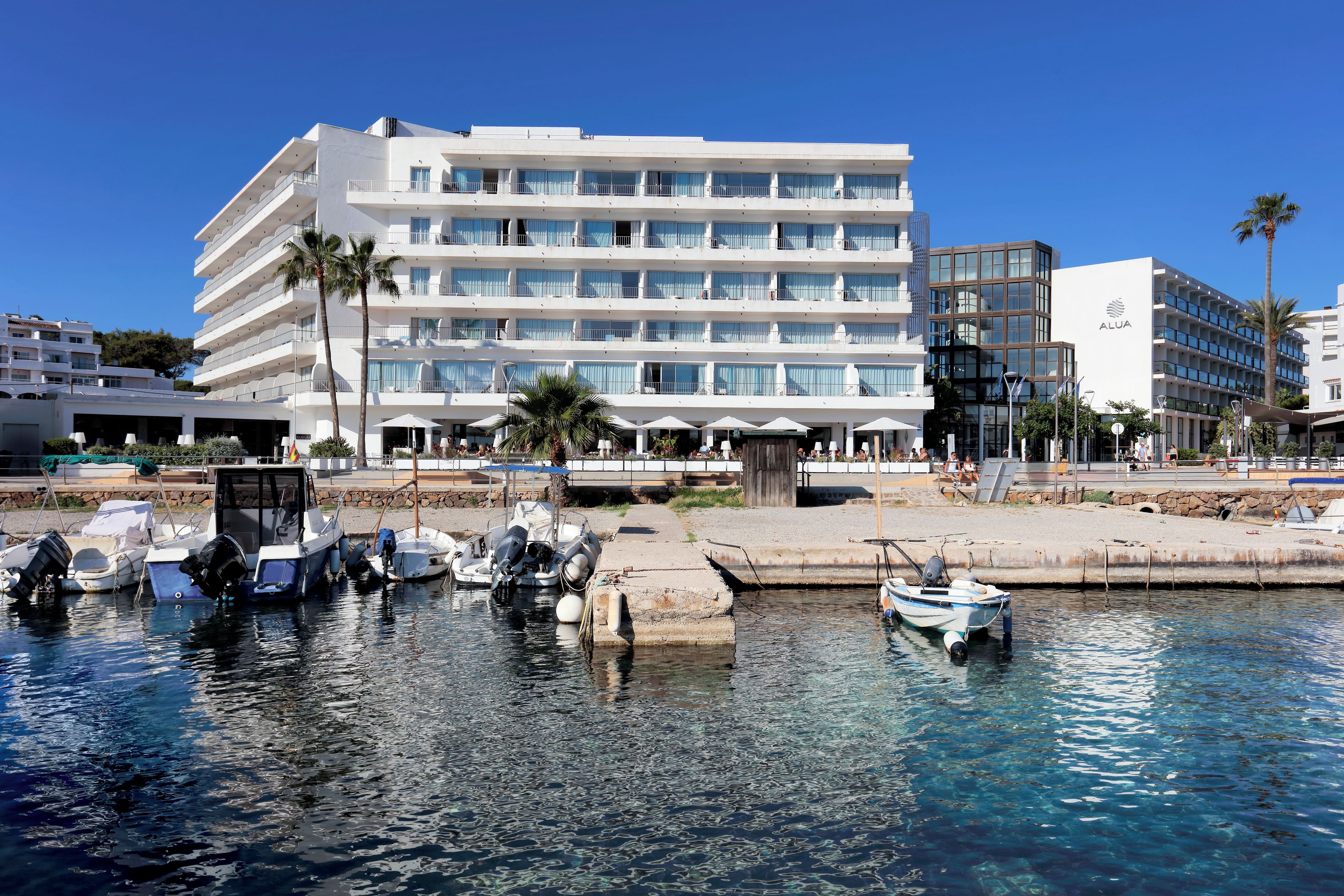 Un hotel de varios pisos con balcones y un puerto deportivo con barcos.