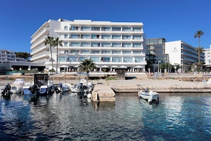 Hotel de vários andares com varandas e uma marina com barcos.