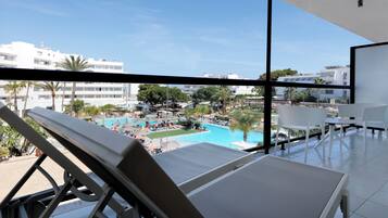 A balcony with a view of a swimming pool and surrounding buildings.