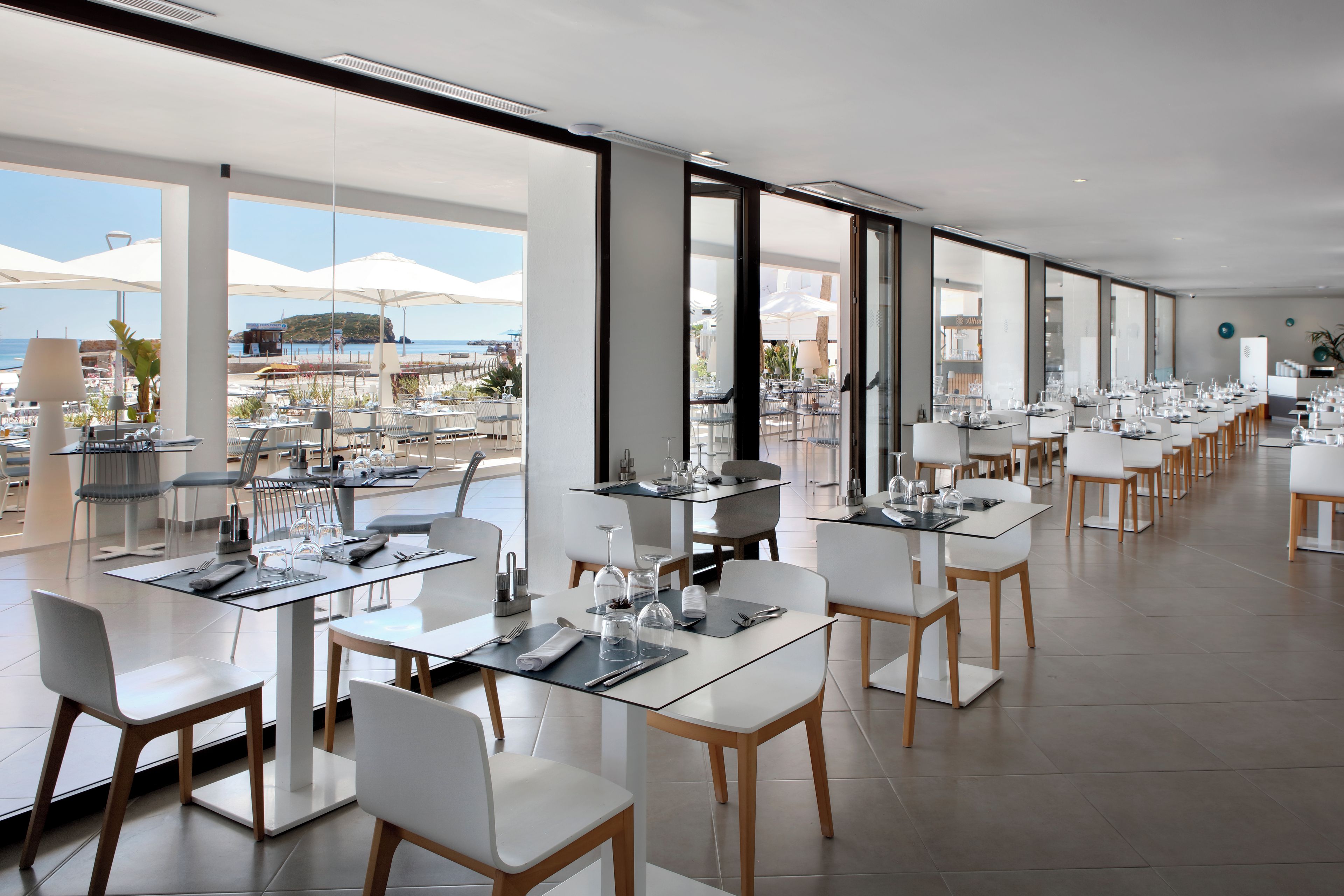 A modern restaurant with a terrace overlooking a coastal area.