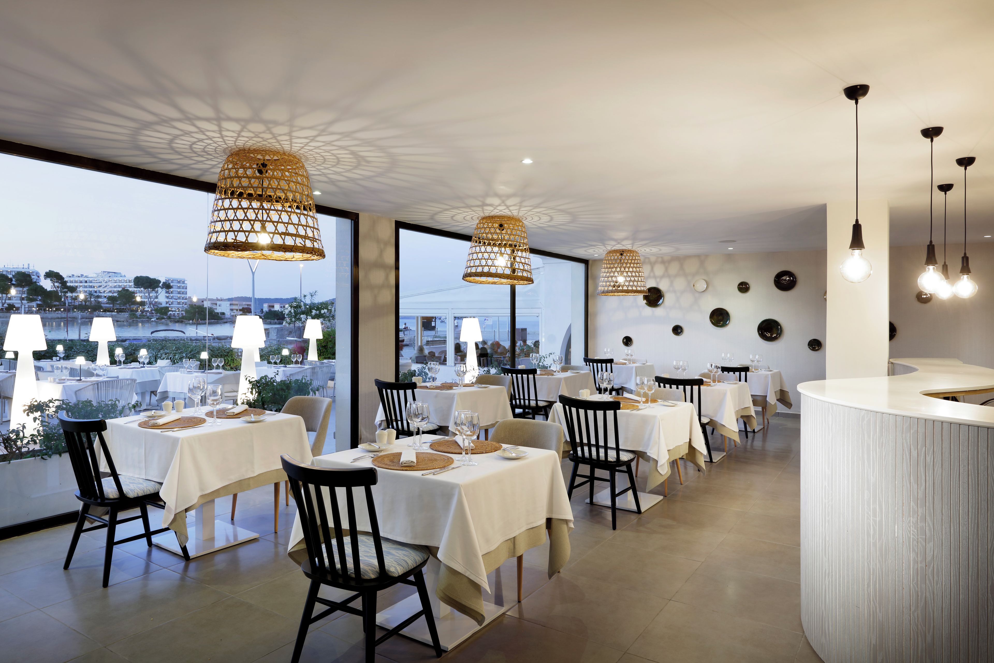 Un restaurante con varias mesas, sillas y lámparas colgantes.