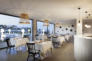 A restaurant with multiple tables, chairs, and hanging pendant lights. - AluaSoul Ibiza -Adults Only - Hyatt Inclusive Collection (Santa Eulalia del Rio)