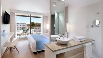 Una camera d'albergo con un letto, una scrivania, un bagno con lavandino e specchio, e vista sulla città.