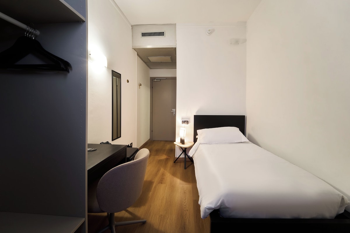 Een hotelkamer met een bed, een bureau, een stoel en een kledingkast.