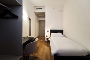 Een hotelkamer met een bed, een bureau, een stoel en een kledingkast.