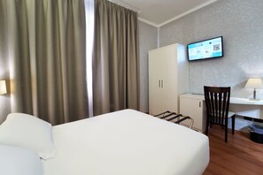 Een hotelkamer met een bed, een bureau, een stoel, een televisie en een kledingkast.