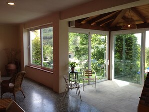 A spacious room with large windows, a dining area with chairs, a table, and a potted plant. - Hotel Casa Lupi (Marciana Marina)
