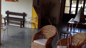 A room with a bench, wicker chairs, a small table, and a window.