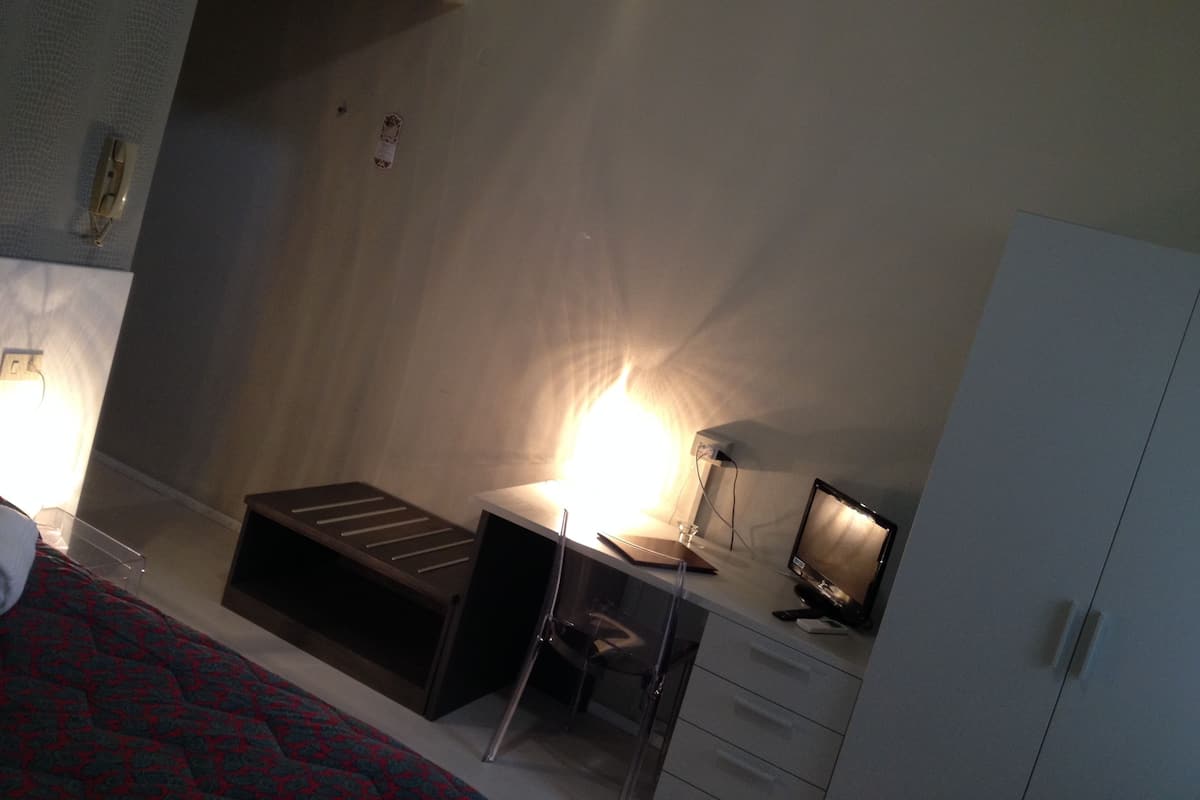 Una habitación pequeña y funcional con cama, escritorio, silla y armario.