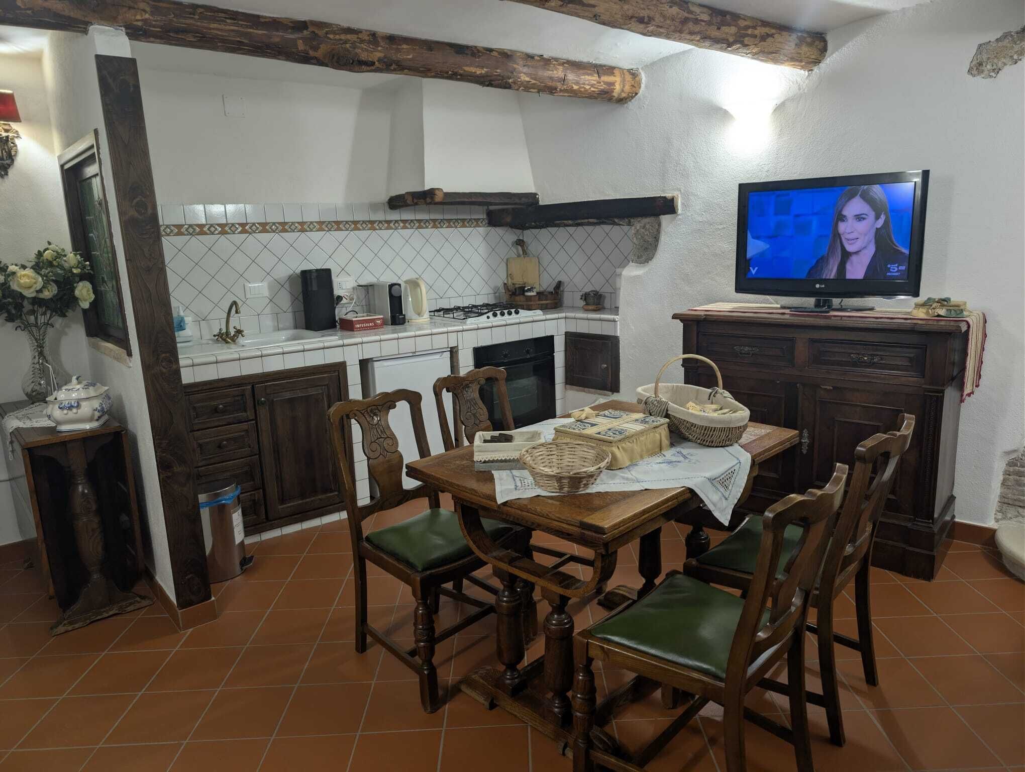 Une cuisine avec des carreaux blancs, des meubles de rangement en bois et une table à manger avec des chaises.