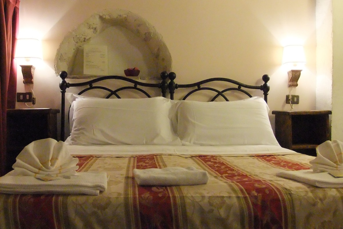 Ein Bett mit Kopfteil, zwei Nachttischen und einer Wandlampe.