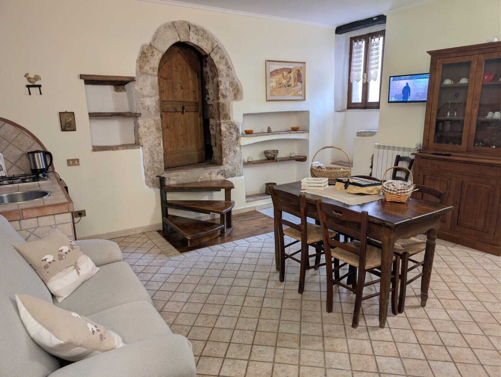A cozy living room with a stone fireplace, a dining area with wooden furniture, and a kitchen with a built-in oven.