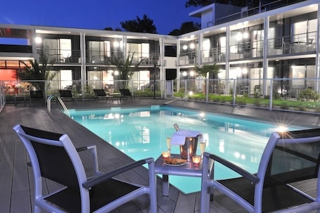 Una piscina al aire libre, sombrillas, sillones reclinables de piscina