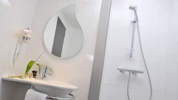Un baño moderno con un lavabo blanco, un espejo y una ducha.