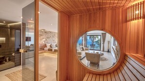 Un interior moderno con un ventanal de madera circular que da a un balcón con mobiliario exterior.