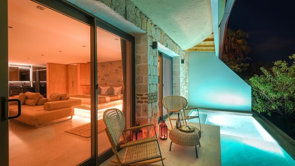 Una sala de estar moderna con un sofá, sillas y un ventanal de vidrio que da a un balcón.