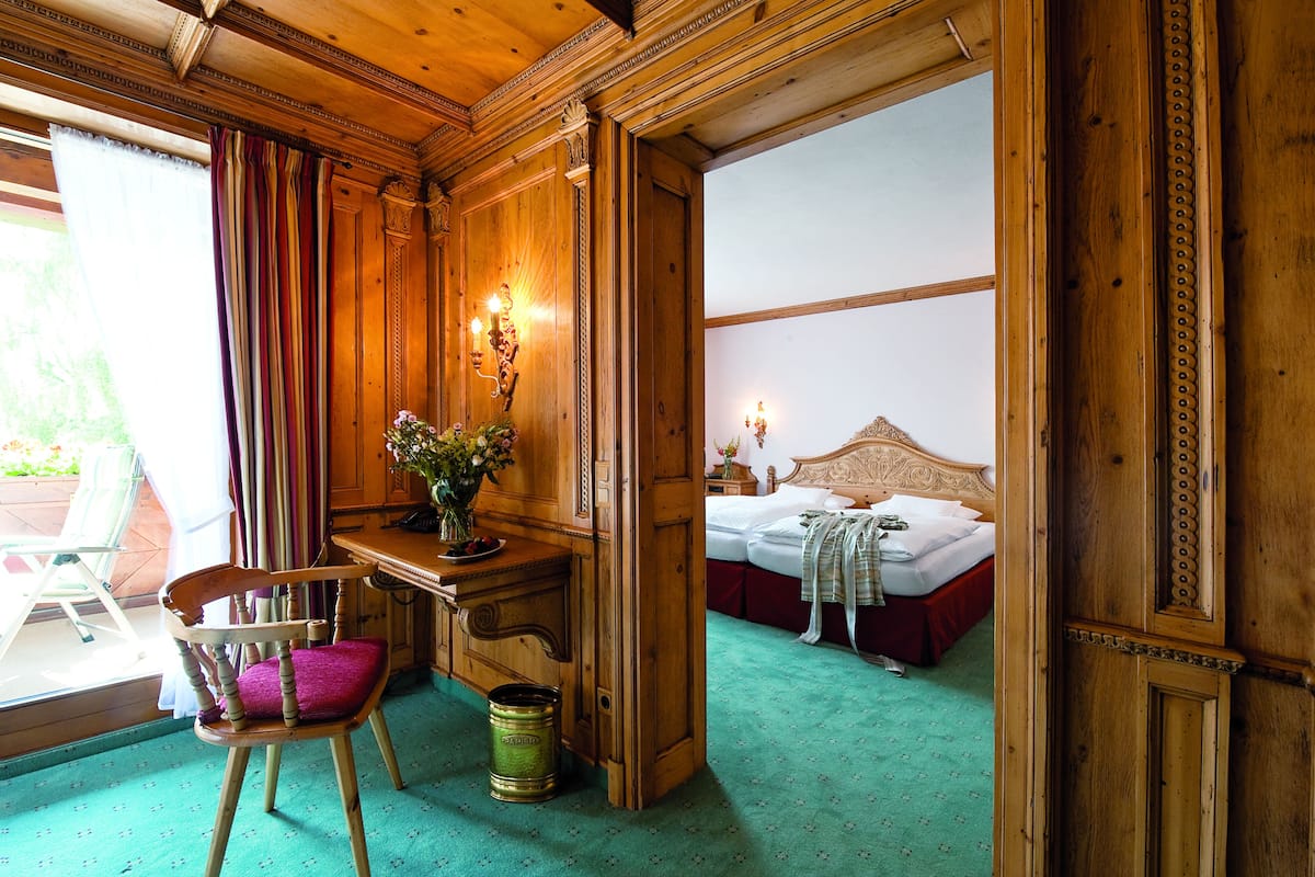 Ein Zimmer aus Holz mit Schreibtisch, Stuhl und Bett.
