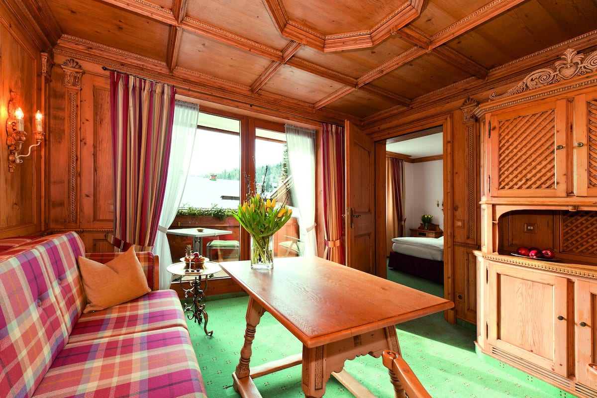 Ein gemütliches Zimmer mit einem karierten Sofa, einem Holztisch mit Blumenvase und einem grünen Teppich.