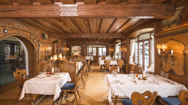 Ein Restaurant mit Holzeinrichtung, mehreren Tischen und Kronleuchtern.