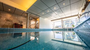 Ein Innenpool mit Steinwänden, einer gefliesten Decke und Blick ins Freie.