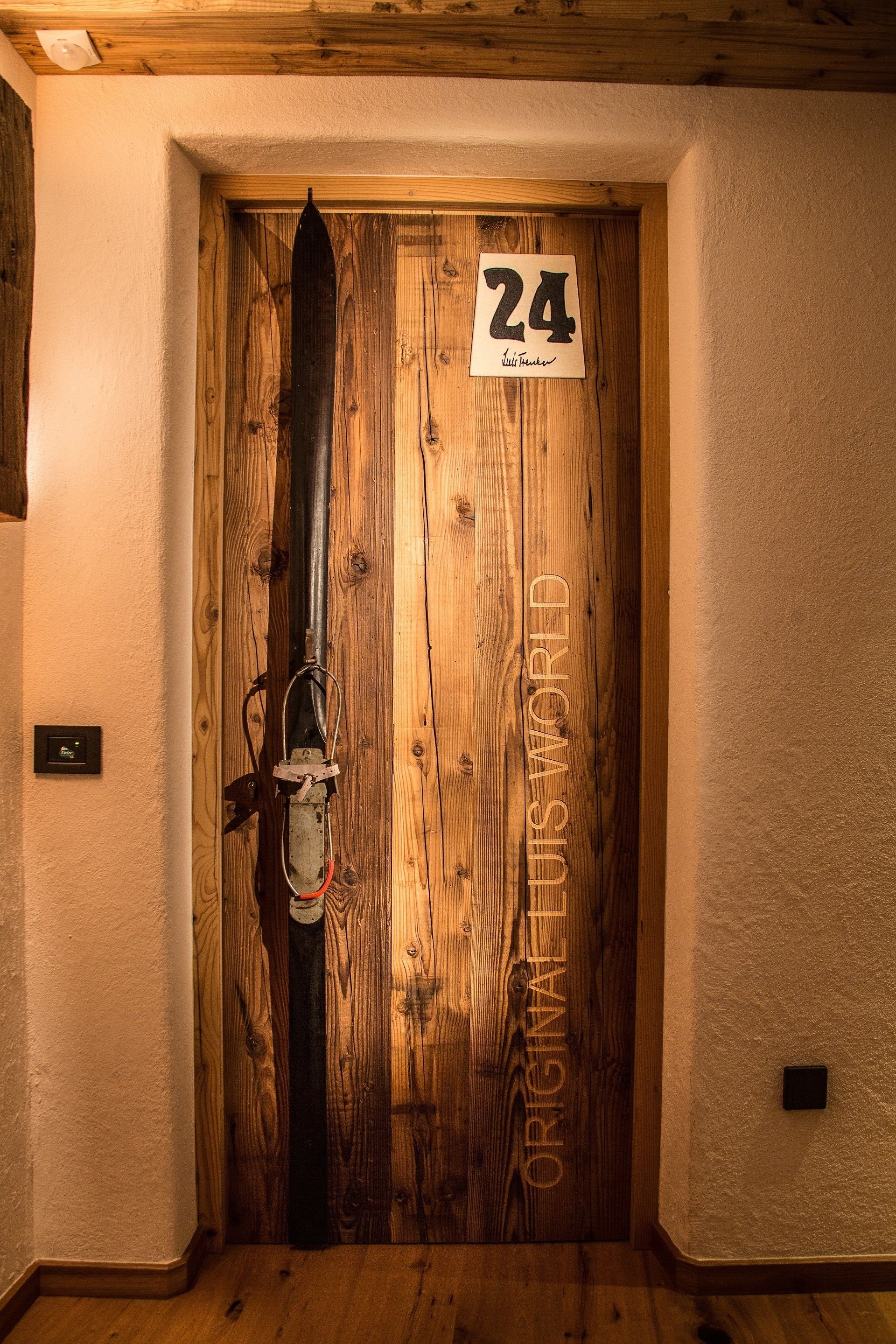 Uma porta de madeira com uma placa com o número 24 e a inscrição 'ORIGINALS WORLD'.