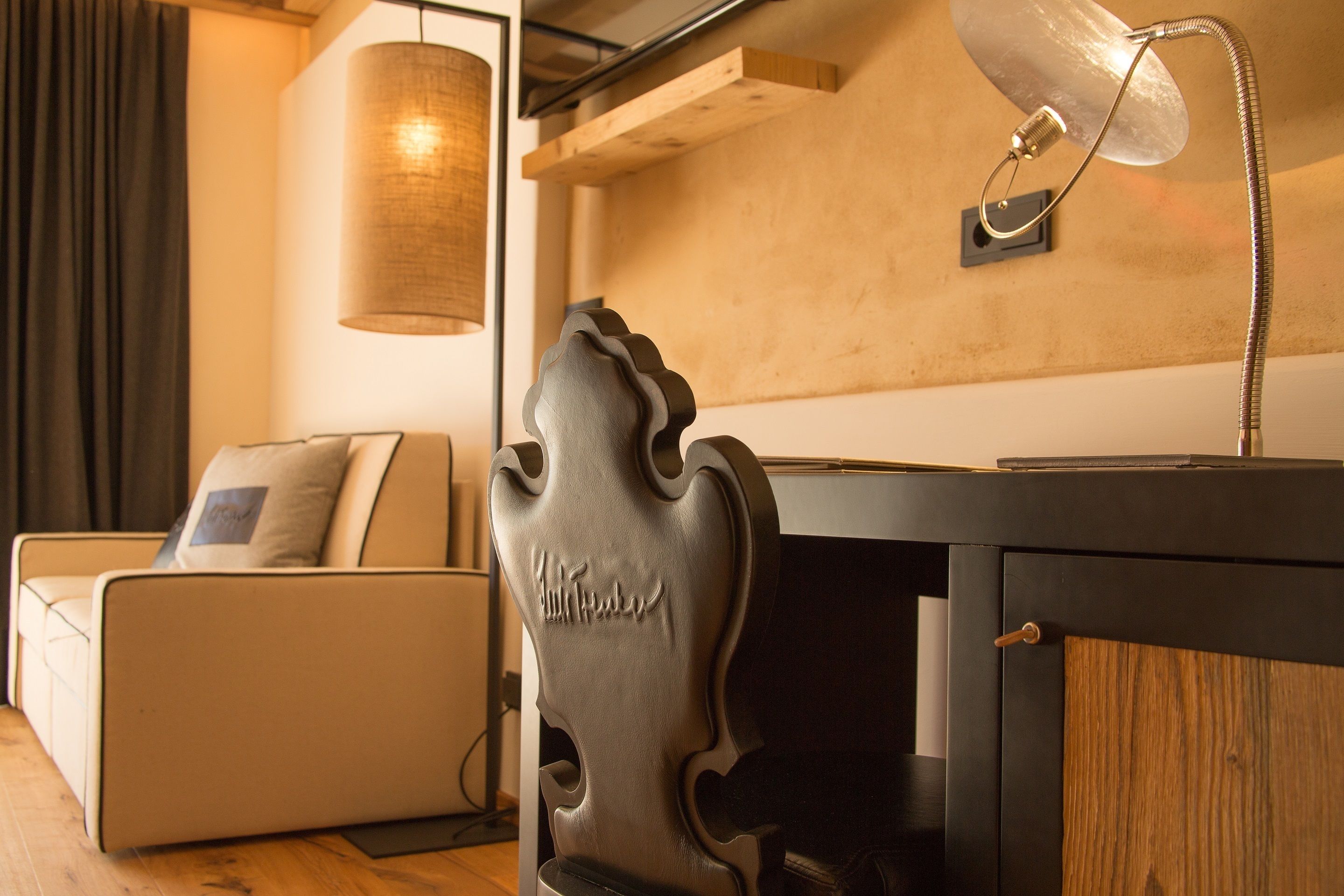 Ein modernes Wohnzimmer mit einer Couch, einem Dekostuhl, einer Lampe und einem Holzschrank.